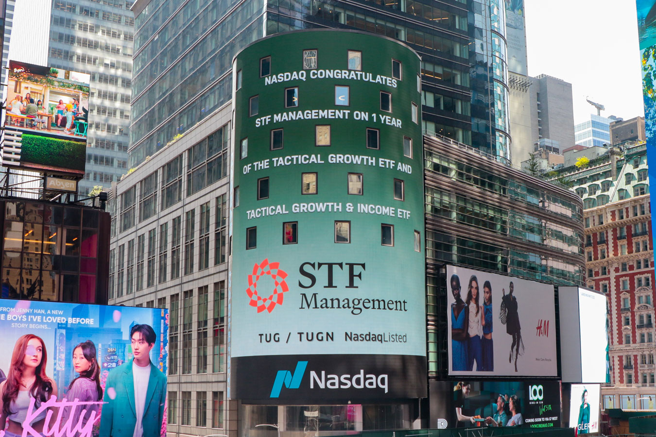 Photo of "STF Management | Nasdaq" on a large display billboard.